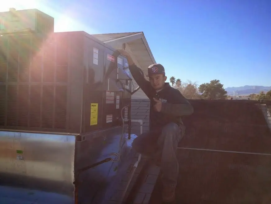 HVAC technician performing AC Tune-Up on a rooftop unit in Carrollton